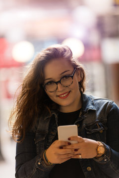 Attractive girl texting on her cellphone outdoors.
