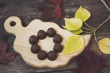 Obraz na płótnie Canvas chocolate candies on a wooden Board with autumn leaves