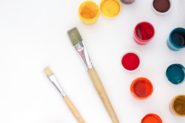 Paint jars and brushes on white background top view