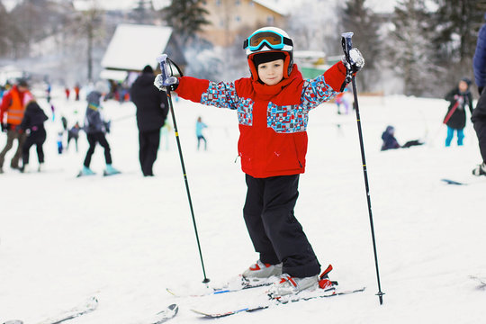 Little cute boy with skis and a ski outfit. Little skier in the ski resort