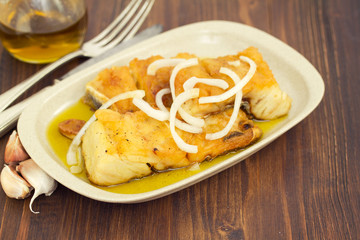 fried cod fish with onion and olive oil on dish