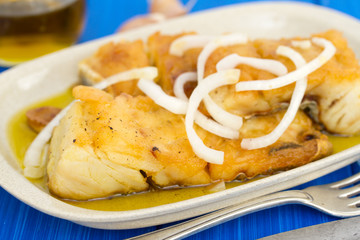 fried cod fish with onion and olive oil on dish