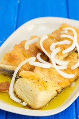 fried cod fish with onion and olive oil on dish