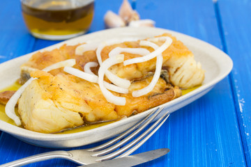fried cod fish with onion and olive oil on dish