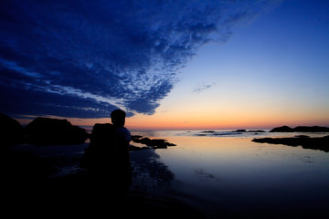 Naklejka na ściany i meble A man waching beautiful sunrise on rocky beach, Bulgarian black sea landscape
