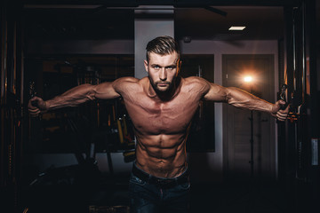 Muscular bodybuilder handsome men doing exercises in gym with naked torso. Strong athletic guy with abdominal muscles and biceps.