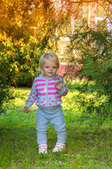 adorable happy baby girl with blond hair walking in the park