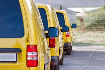 Yellow courier or taxi cars are lined up in the parking lot.
