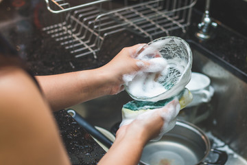 A woman washing bowl glass by dish soap make many bubble