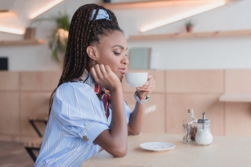 Obraz na płótnie Canvas african american woman drinking coffee in cafe