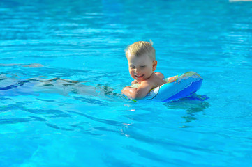 Fototapeta na wymiar the little blonde boy of three years swim with swimming ring in an indoor pool