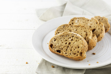 fresh wholemeal bread on a plate, on a white painted rustic wooden table, copy space
