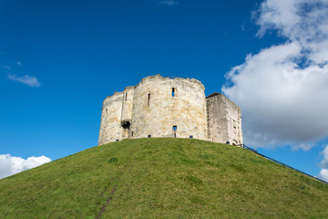 Fototapeta na wymiar Clifford's Tower on grass covered hill with blue sky