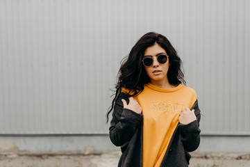 Portrait of stylish modern young curly woman in coat sunglasses