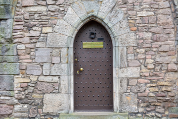 Brown wooden door with a stone wall