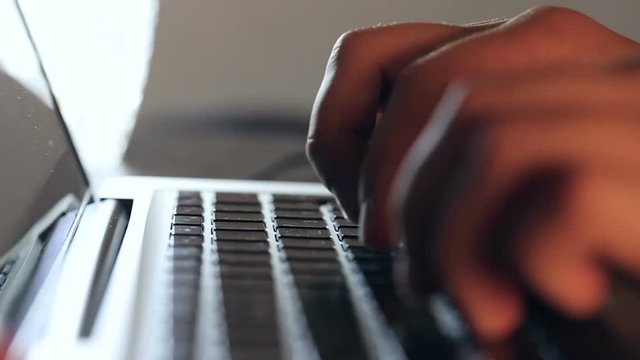 Closeup refocusing shot of writer's hands typing on a laptop keyboard.