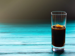 Glass of iced coffee on dark green and black background
