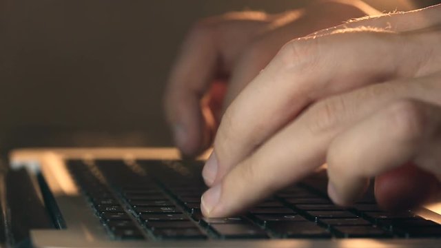 Closeup refocusing shot of programmer's hands typing code on a laptop's keyboard.