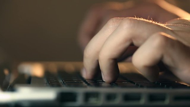 Closeup refocusing shot of programmer's hands typing code on a laptop's keyboard.