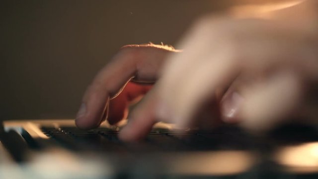 Extremely close-up refocusing shot of programmer's hands typing commands on laptop keyboard. Man using the keyboard for developing application.