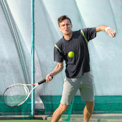 A professional tennis player plays tennis on the court. The ball is suspended in the air.