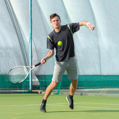 Professional tennis player playing a game of tennis on a court. The ball is suspended in the air.