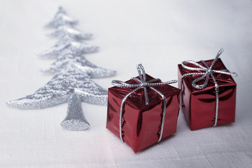 Silver christmas tree and gifts on white textile background