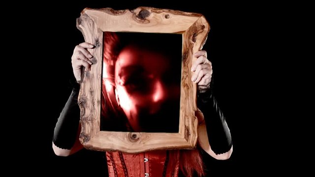 A sexy girl holding a wooden frame with a scene: a cursed doll rotating. Red dramatic colors.
