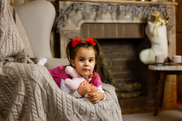 Fototapeta premium Little girl near fireplace holding soft toy in hand.