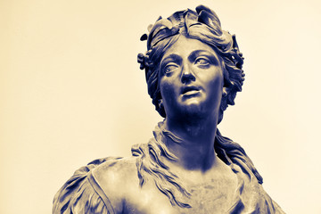 Ancient female statue of 18th century outdoor in park. Public domain. Nymph with a hoop of flowers, laurel leaves on her head. Beautiful photo for art calendars, prints, posters, design, cards. Stone.
