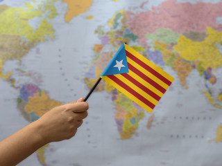 A flag of Catalonia on the background of the world map. 