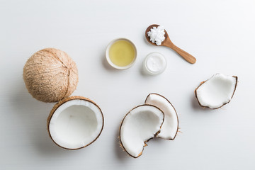 Homemade coconut products on white wooden table background. Oil, scrub, milk and lotion from top view. Good for space and background.