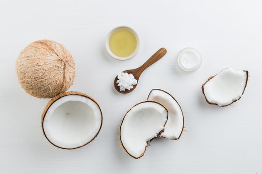 Homemade coconut products on white wooden table background. Oil, scrub, milk and lotion from top view. Good for space and background.
