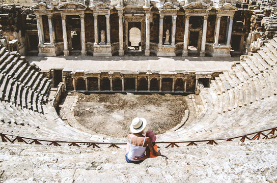 Mom and daughter are sitting on the steps of an ancient amphitheater, located in Hierapolis, Pamukkale, Denizli province, Turkey.