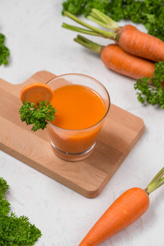 Glass of fresh carrot juice with vegetables on table.