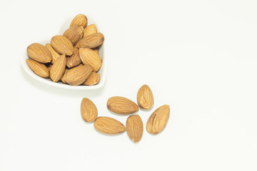 Almond seed in a heart-shaped ceramic cup on a white background