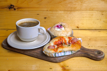 Cup of coffee ,muffin and mini pizza on wooden cutting board