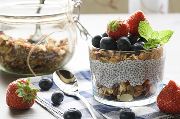 Yogurt with granola, fresh blueberries, chia seeds and oats in a glass over wood background. close up