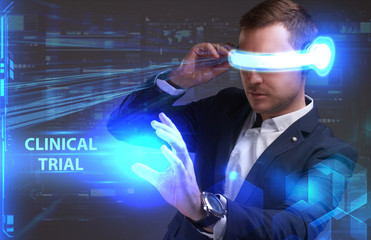 Business, Technology, Internet and network concept. Young businessman working in virtual reality glasses sees the inscription: Clinical trial