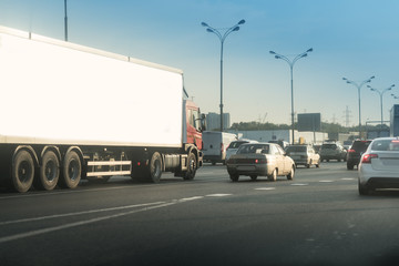 Obraz na płótnie Canvas Highway traffic in sunset with cars and truck with white trailer