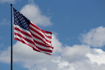 Flag of the United States of America (USA) fluttering in the wind against the background of the sky and clouds