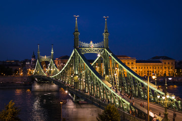 Obraz premium Budapest, capital of Hungary, night panorama. The illuminated Liberty Bridge on the river Danube, and University of Economics on the Pest side.