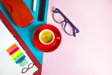 bright office supplies on a multi-colored combined background with glasses and an espresso cup. Flat lay. Top view. Copyspace