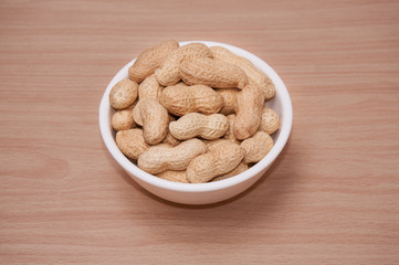 Peanuts with a brownish background of light wood.