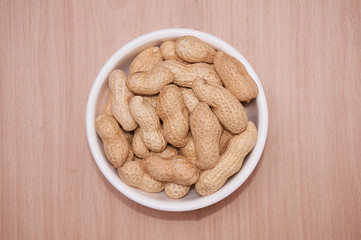 Peanuts with a brownish background of light wood.