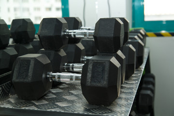 Obraz premium Gym. Gymnasium with sports equipment. Dumbbells, barbells, dumbbells - equipment to work on muscle mass. Morning exercises for vitality afternoon. Rows of dumbbells in the gym.