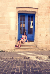 Fototapeta na wymiar Elegant brunette model in trendy lace dress holding bouquet of flowers. Woman sitting at the door.