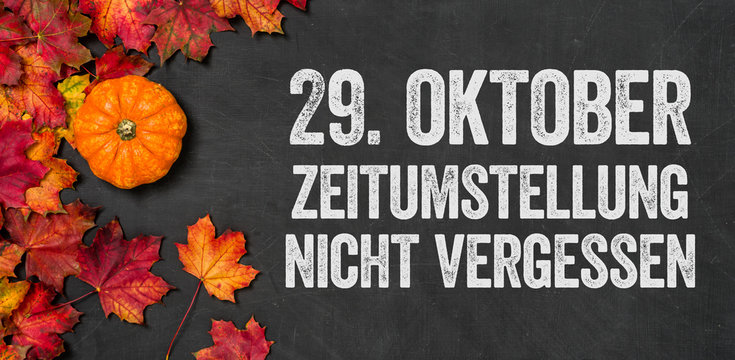 Herbstlaub mit K&uuml;rbis auf einem dunklen Hintergrund - Zeitumstellung