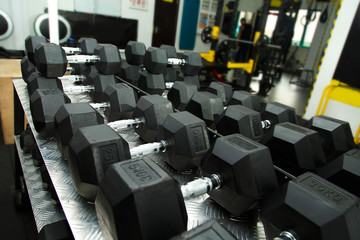 Obraz premium Gym. Gymnasium with sports equipment. Dumbbells, barbells, dumbbells - equipment to work on muscle mass. Morning exercises for vitality afternoon. Rows of dumbbells in the gym.