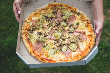 Pizza with prosciutto and artichokes in a box
